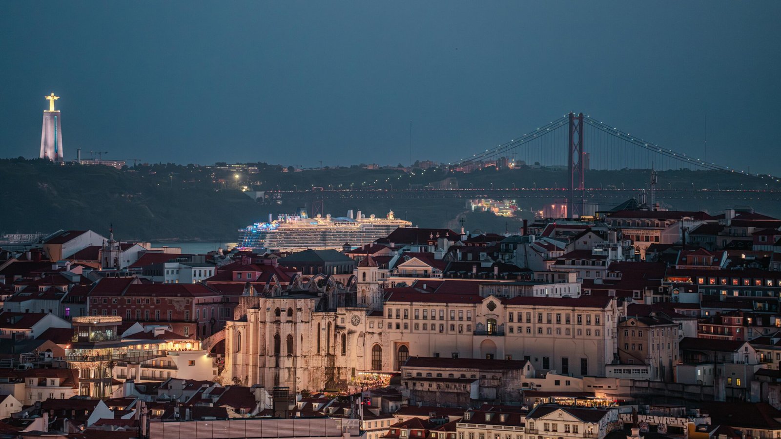 Stunning view of Lisbon at dusk, featuring the Ponte 25 de Abril and Christ the King statue.