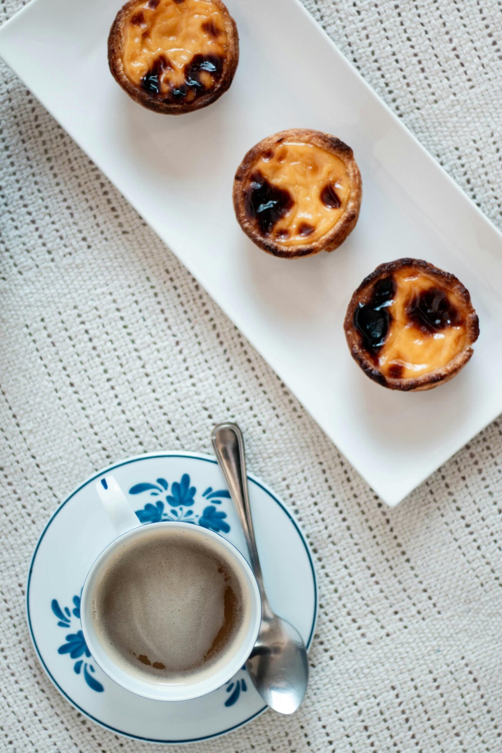 Portuguese egg tarts and a ceramic cup of coffee create a delightful food scene.